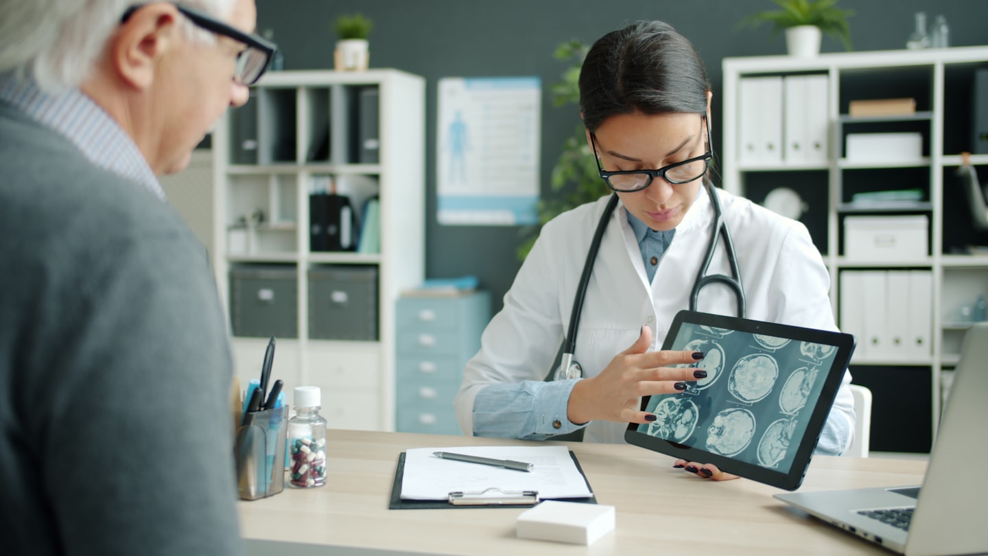 Doctor explaining medical scans on a tablet to a patient.